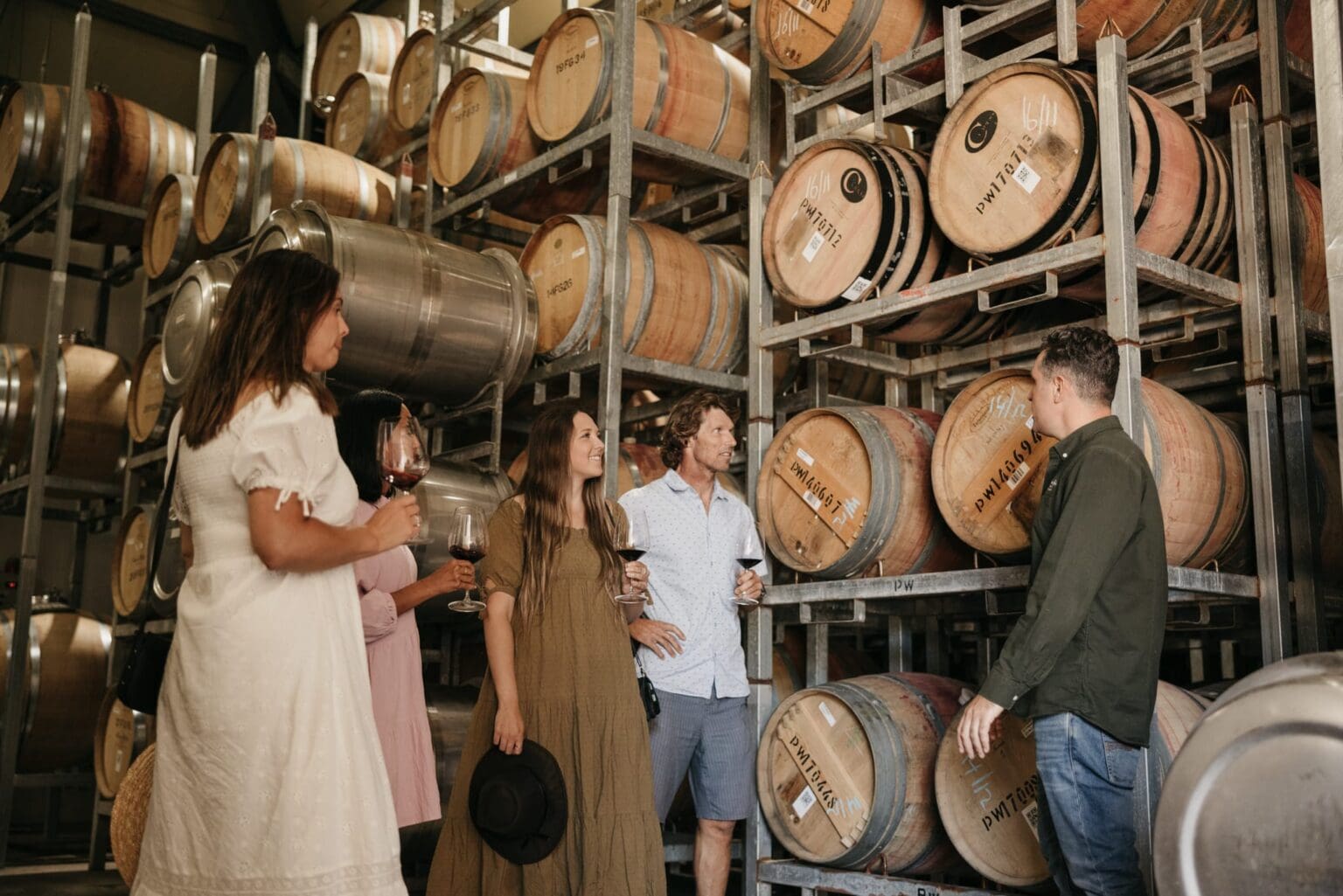 A group of people with barrels of wine surrounding them.