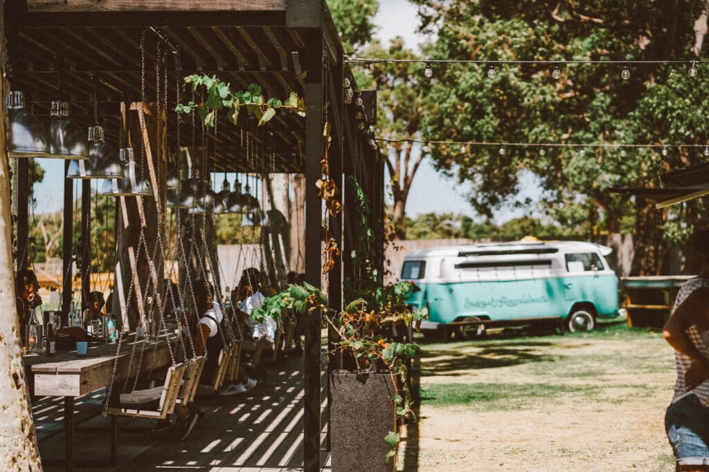 Swinging chairs on an outside deck are positioned in front of A blue Kombi Van