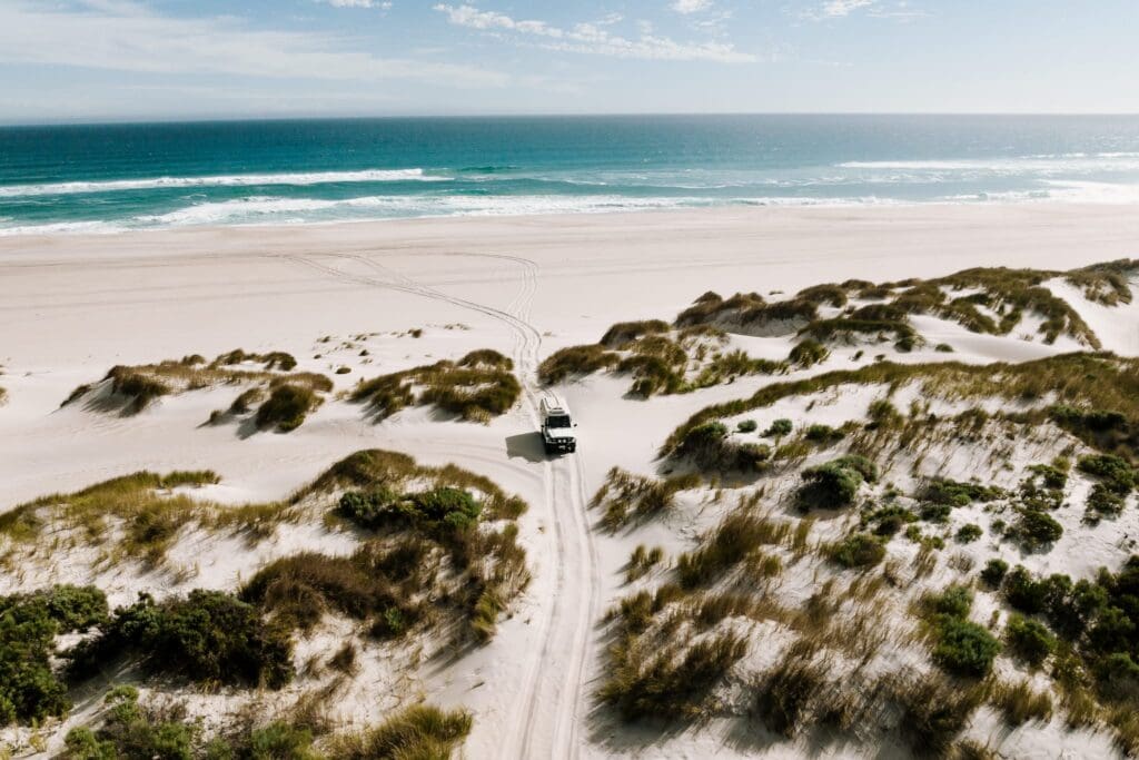 Four-wheel drive croses teh sandy dunes at Yeagarup, with the beautiful Indian Ocean in the background.