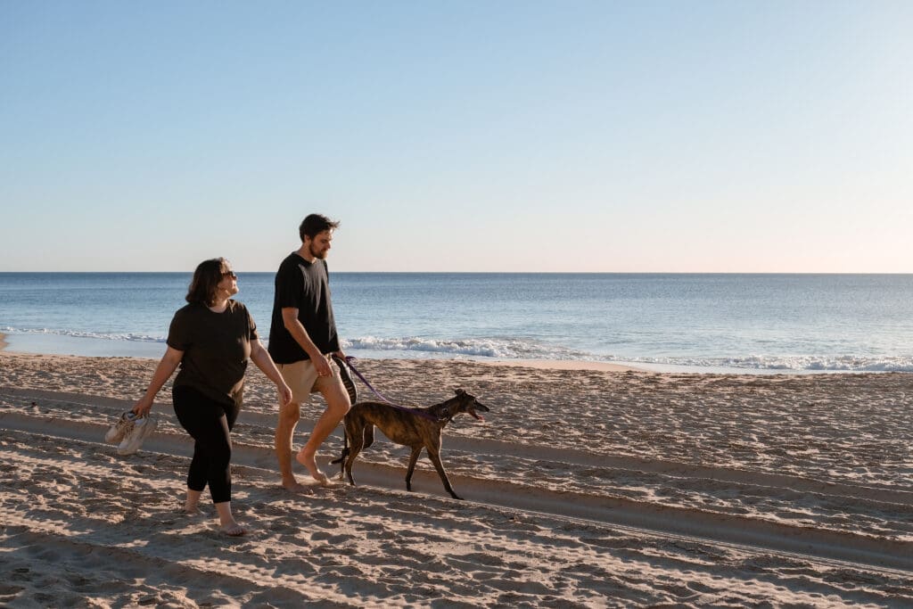 Two people walking their dog on Dalyellup Beach